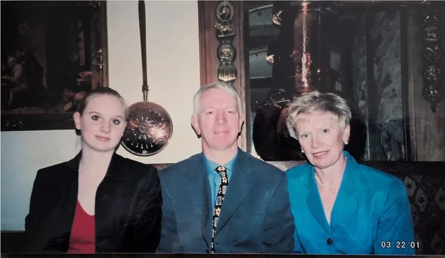 Iain and Pam seated with a Anda at a table, dressed smartly for the occasion.