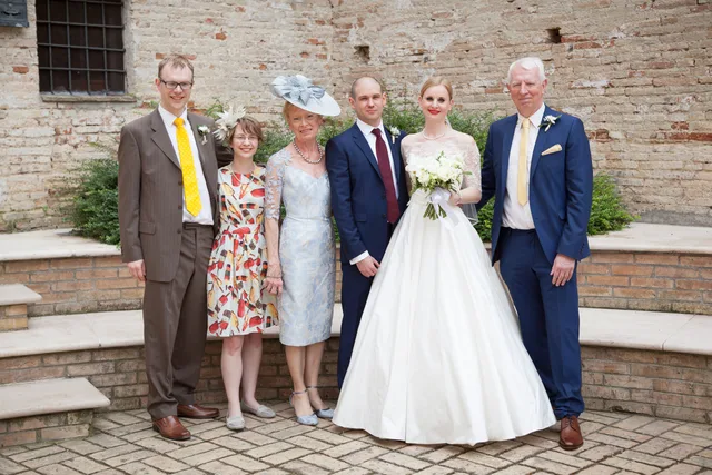 Iain and Pam pictured with family at a wedding, Pam in a pale blue dress.