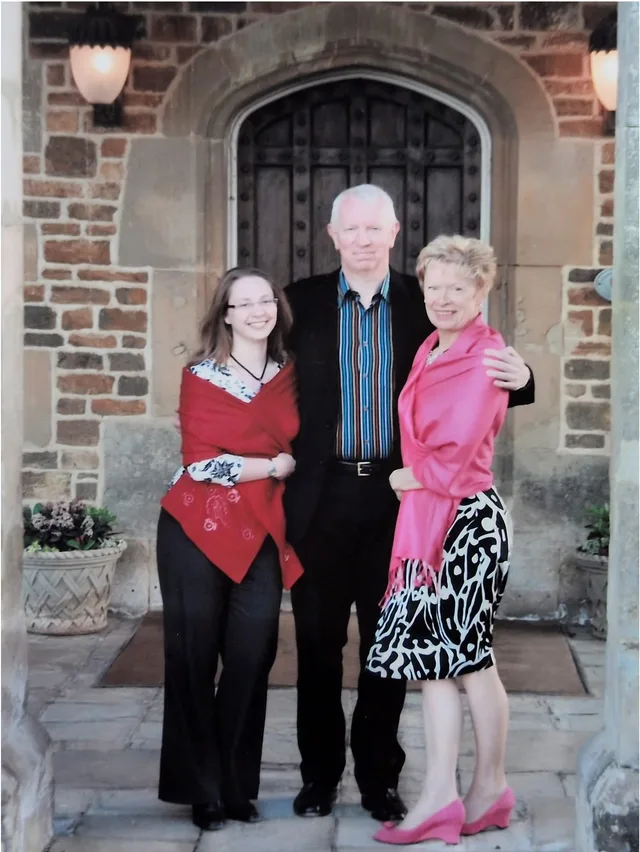 Iain and Pam with Chloe standing beneath the stone archway at Fawsley Hall, dressed for an evening out.